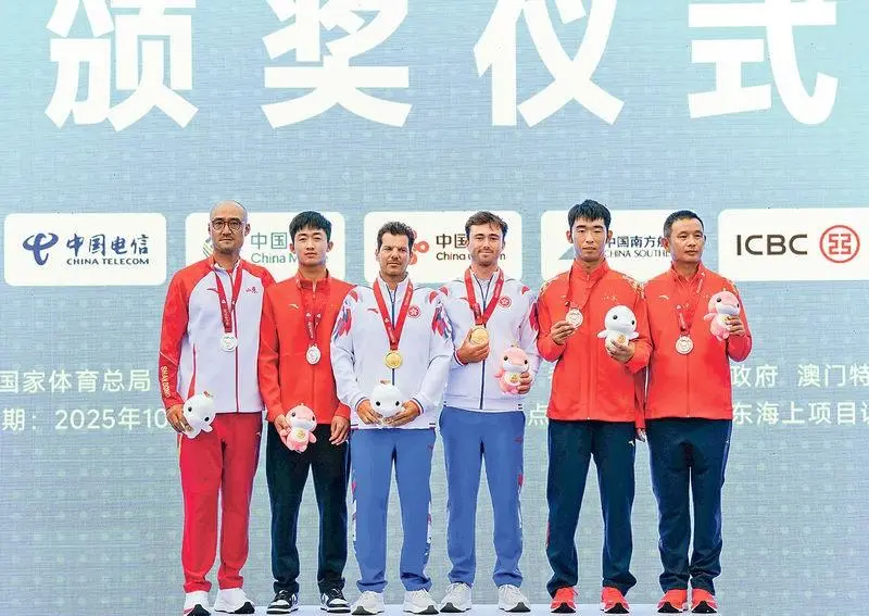 全運會帆船港隊代表貝俊龍(右三)在男子ILCA 7級賽事勇奪金牌,與總教練Harris Tsolis(左三)一同站上頒獎台。旁為銀牌得主山西隊選手唐元帥(左二)和銅牌得主江蘇隊選手羅軍鎖(右二)。(圖片來源﹕新華社)